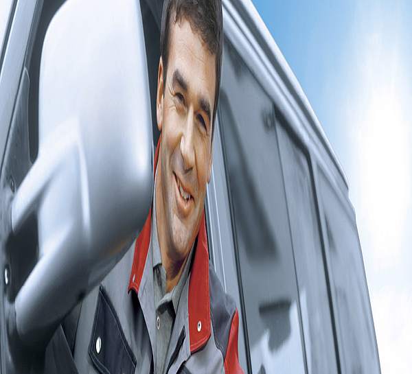 Handwerker sitzt im Auto und lächelt raus
